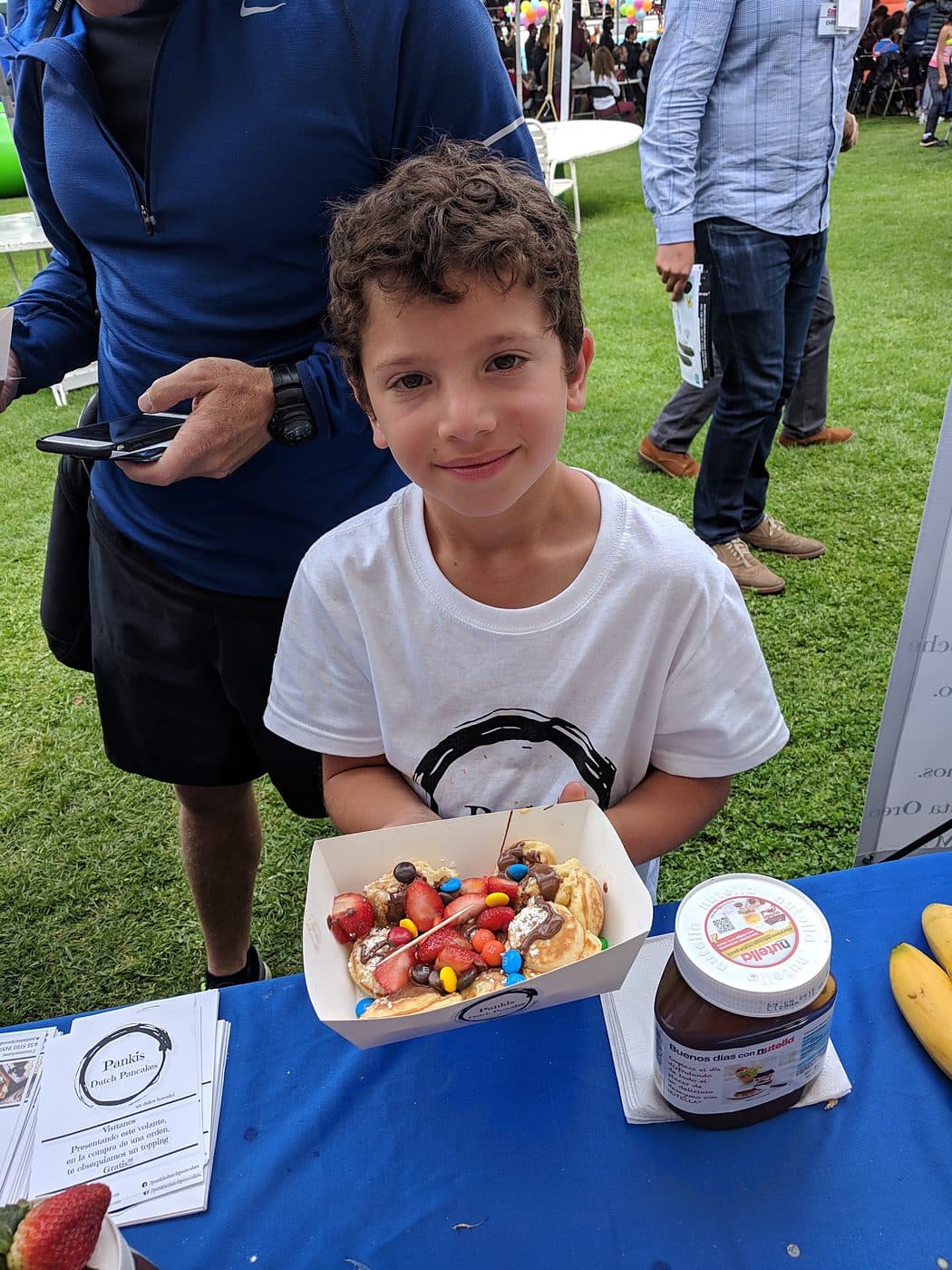 A young guest holding a boat of mini pancakes at an outdoor party