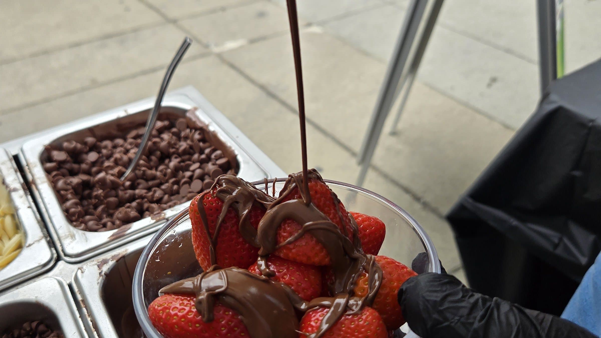 Melted chocolate being poured over a bowl of fresh strawberries at a Pankis event
