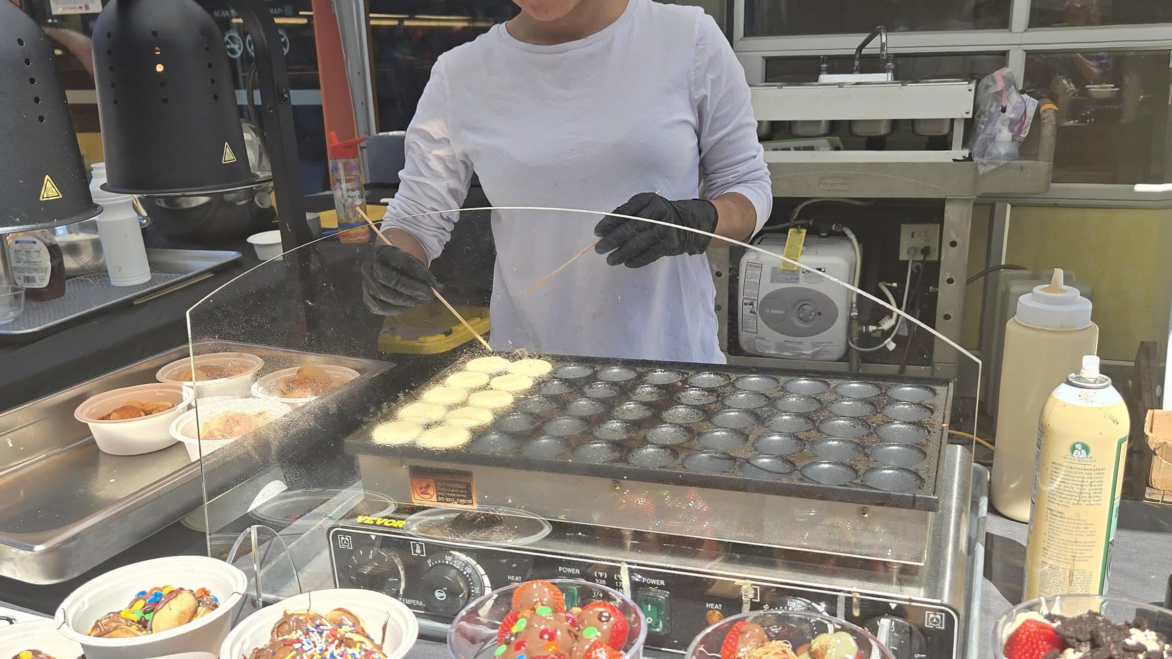 Cooking Dutch mini pancakes on the griddle at a Pankis dessert station