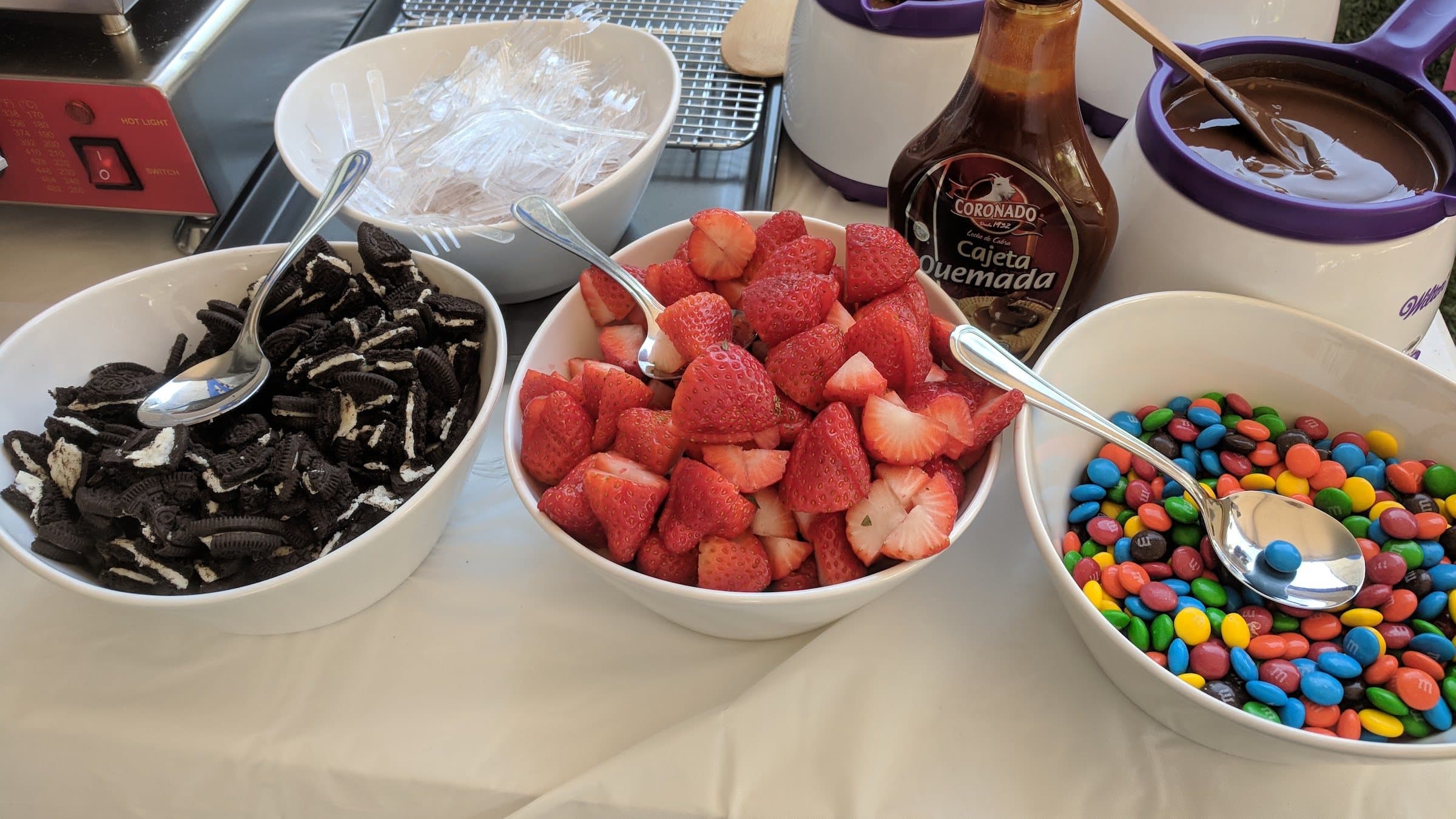 Toppings bar with crushed Oreos, fresh strawberries and M&M's beside the Pankis mini pancake cart