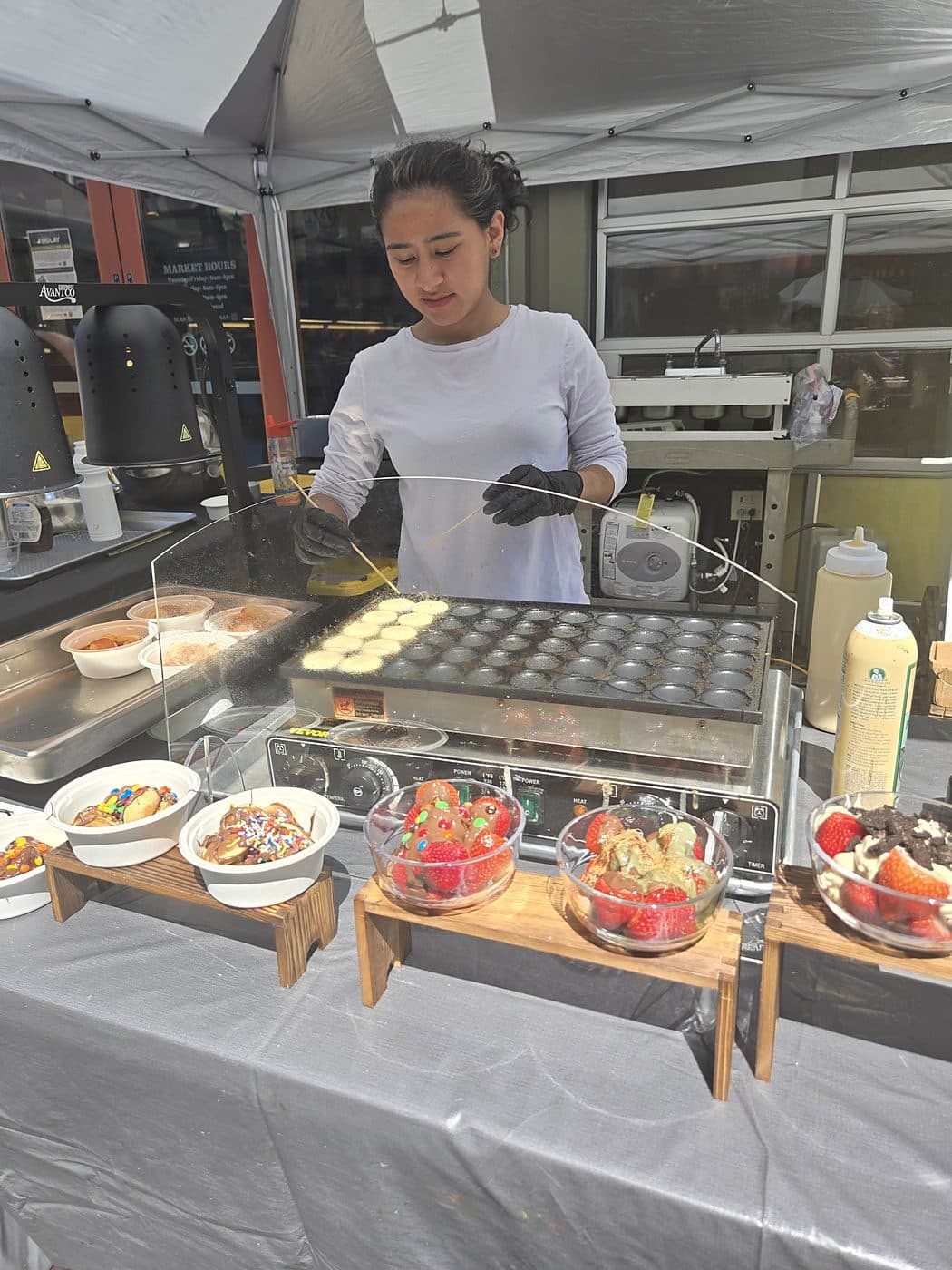 Cooking Dutch mini pancakes on the griddle at the Pankis market stall