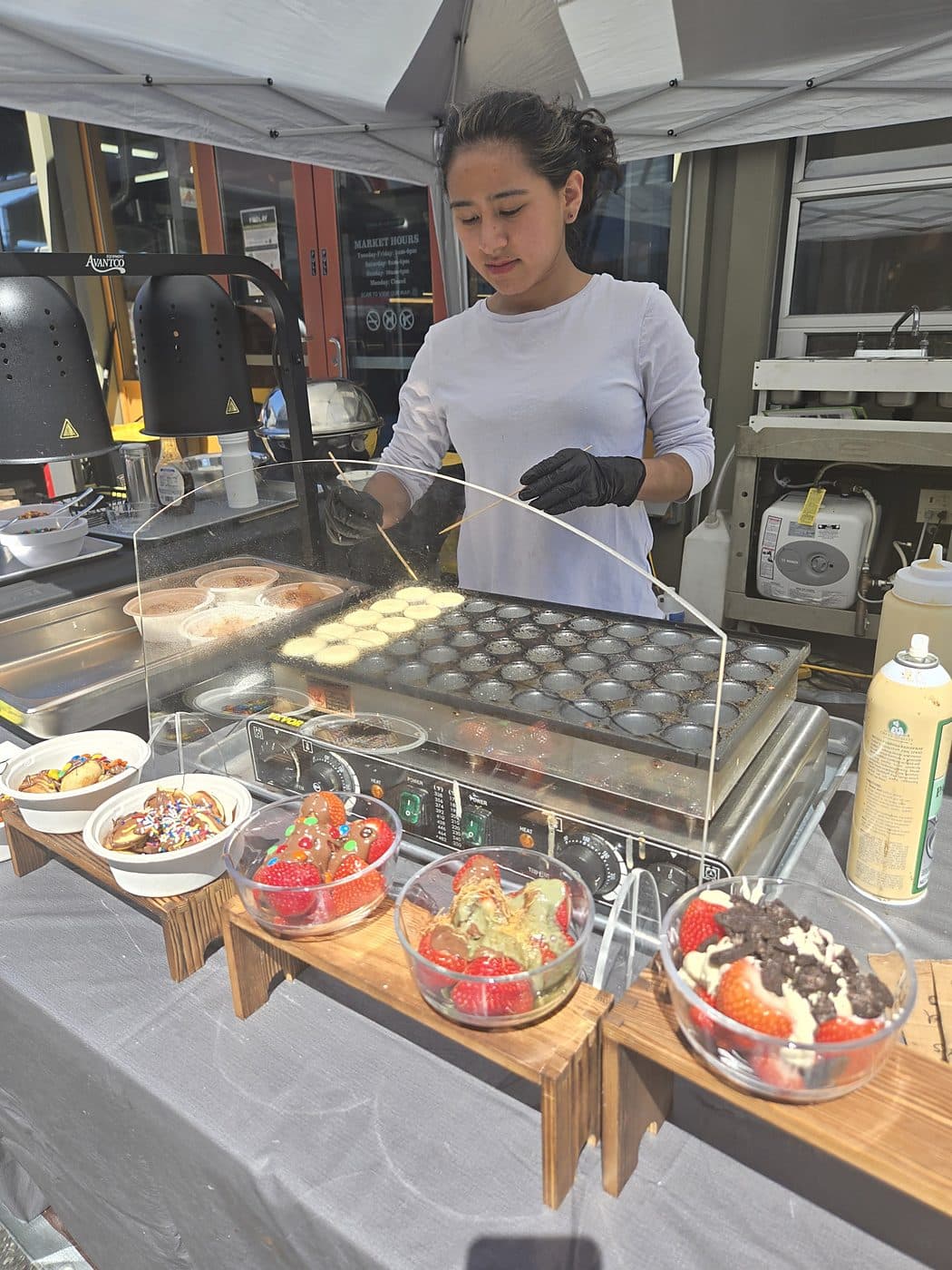 Serving Dutch mini pancakes from the Pankis stall with strawberry cups on the counter