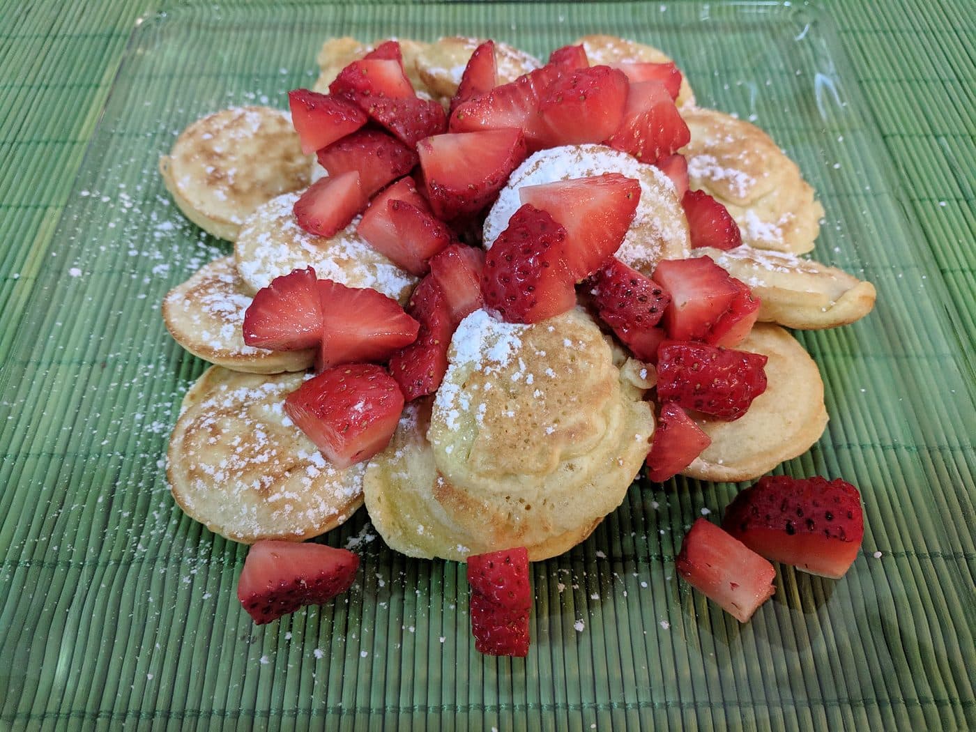 Dutch poffertjes plated with fresh strawberries and powdered sugar