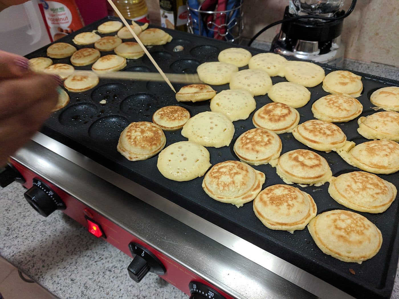 Close-up of Dutch mini pancakes browning on the poffertjes griddle