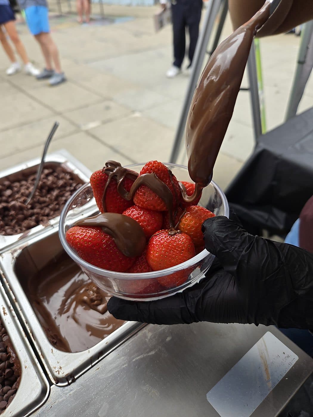 Chocolate-coated strawberries lifted from the dipping tray in a glass bowl