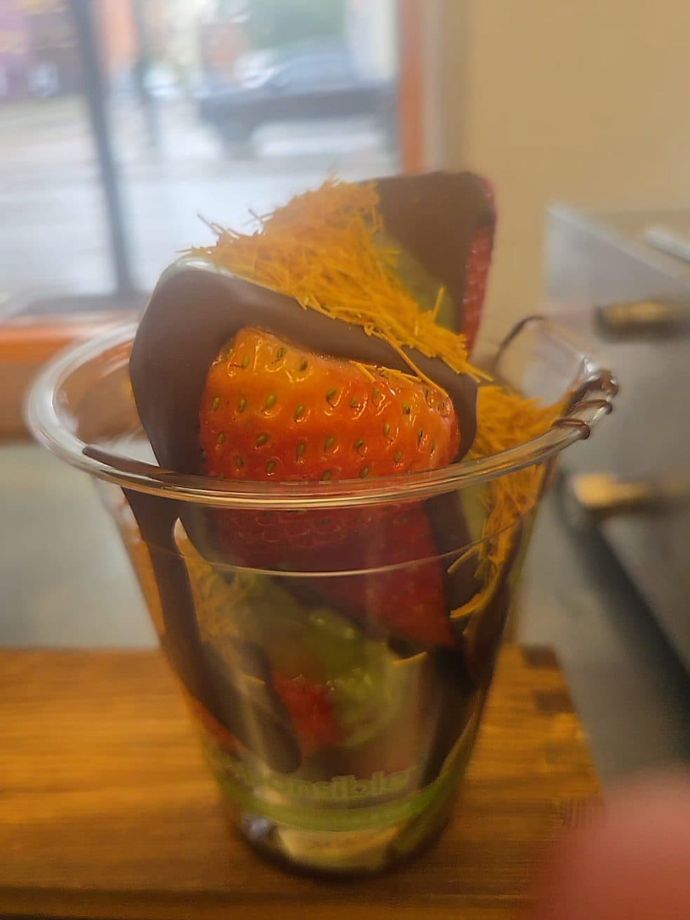 A chocolate-dipped strawberry topped with golden toasted kanafe