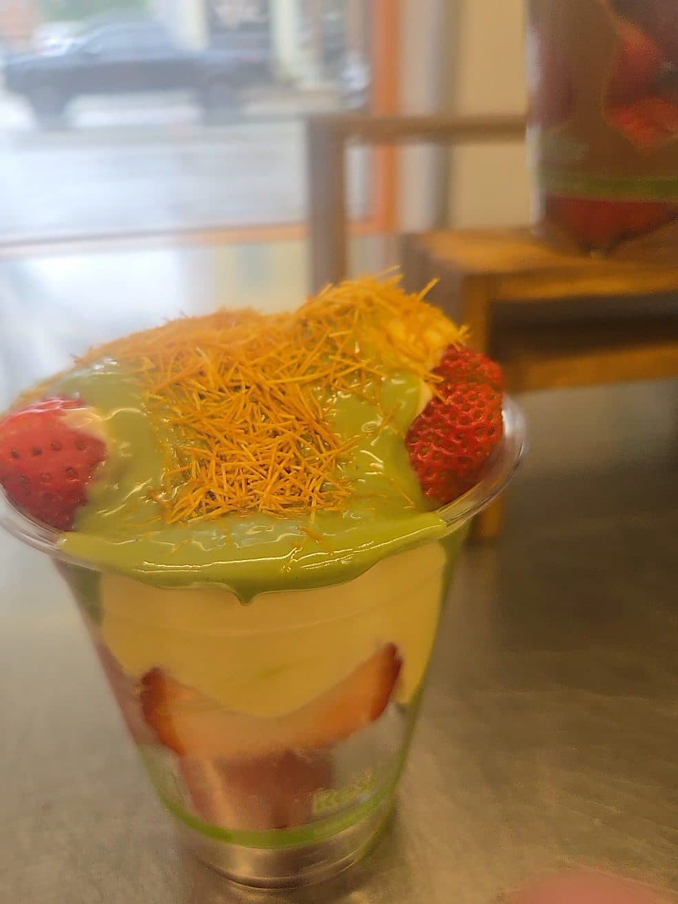 A strawberry cup layered with Dubai-style pistachio cream and toasted kanafe