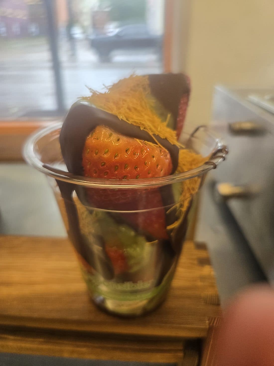 A chocolate-dipped strawberry topped with Dubai-style pistachio cream and toasted kanafe
